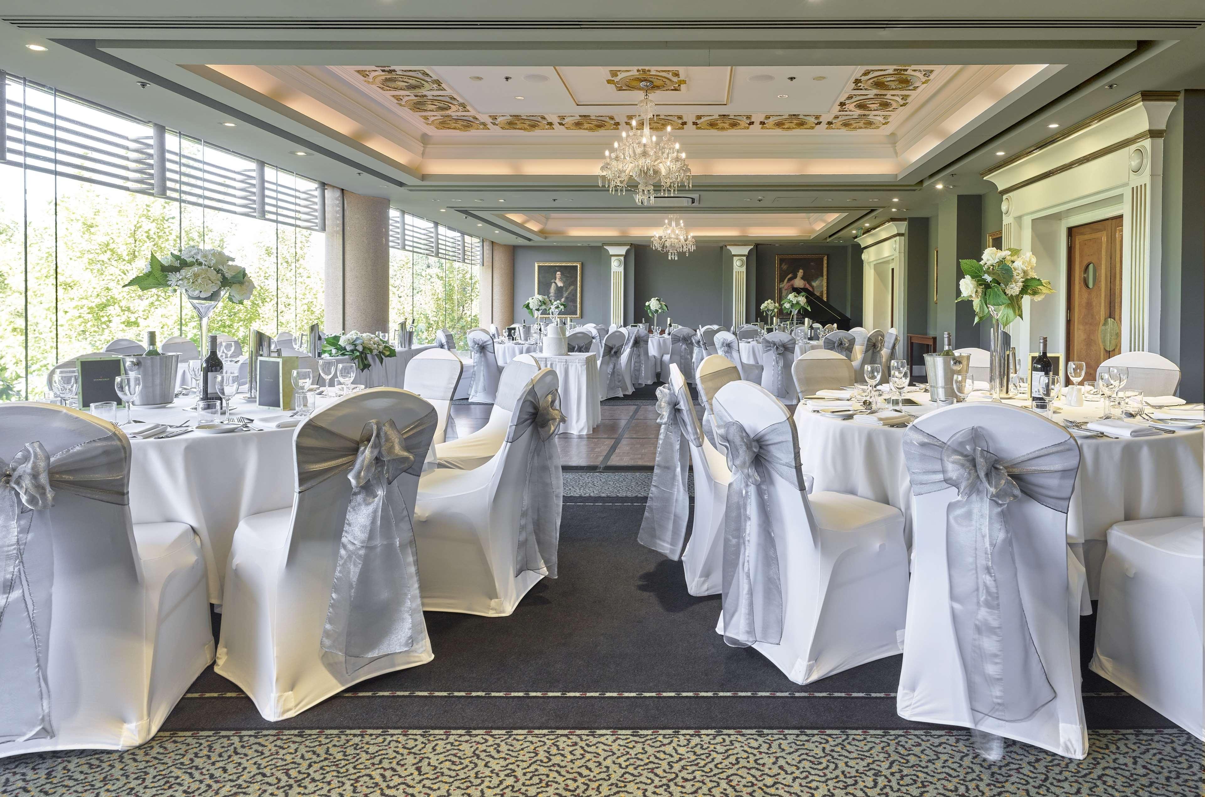 Stamford Plaza Adelaide Hotel Buitenkant foto The photo displays an elegantly arranged banquet hall. The room features several round tables covered with white tablecloths, each adorned with silver sashes on the chairs. There are floral centerpieces, possibly white flowers, on the tables, adding 